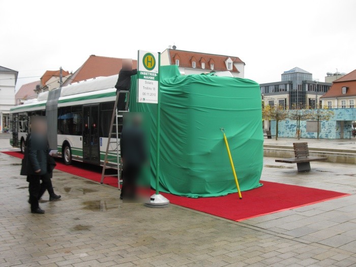 Eine Haltestelle wird aufgebaut und die Front des Gelenkobusses mit einem grünen Tuch verhüllt.